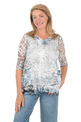 Woman wearing a patterned blouse with sheer sleeves on a white background.