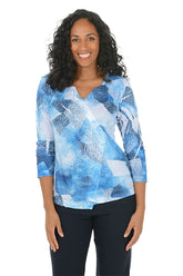 Woman wearing a blue abstract patterned top on a white background.