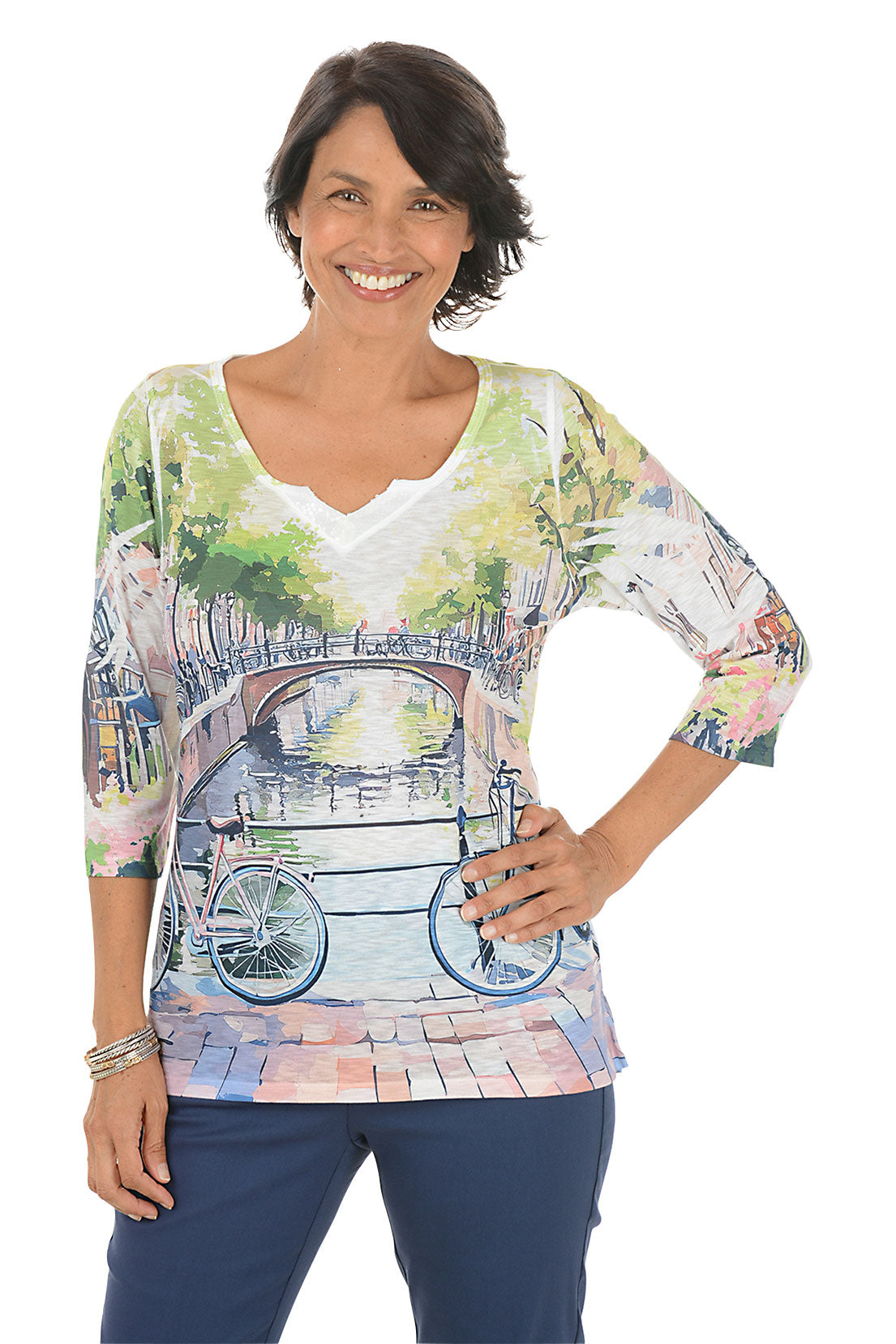 Woman wearing a colorful shirt with a bridge and bicycle design on a white background.