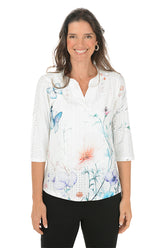 Woman wearing a white blouse with colorful floral pattern on a white background.