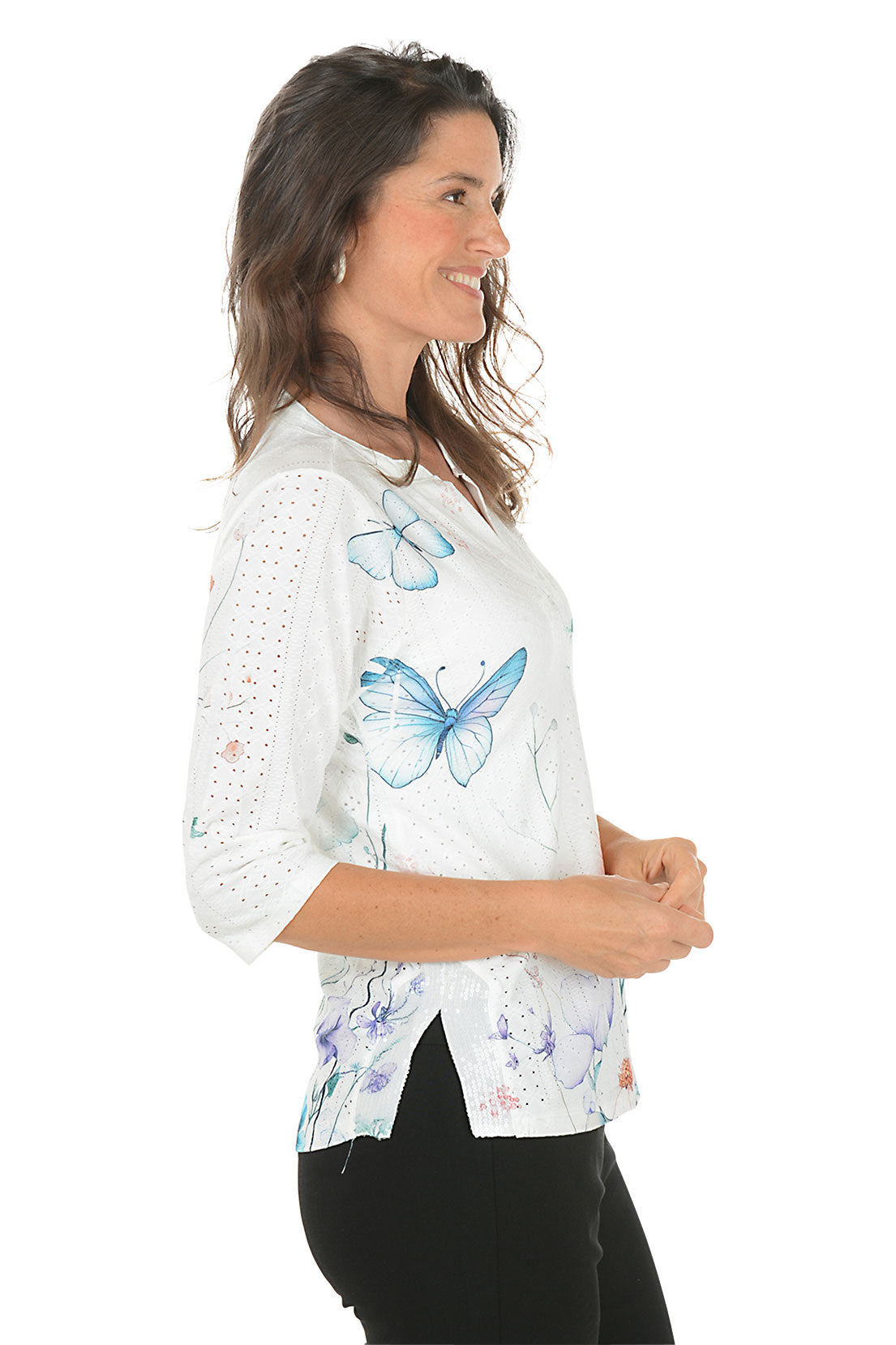 Woman wearing a white blouse with colorful floral pattern on a white background. Side shot.