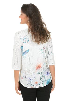 Woman wearing a white blouse with colorful floral pattern on a white background. Back shot.