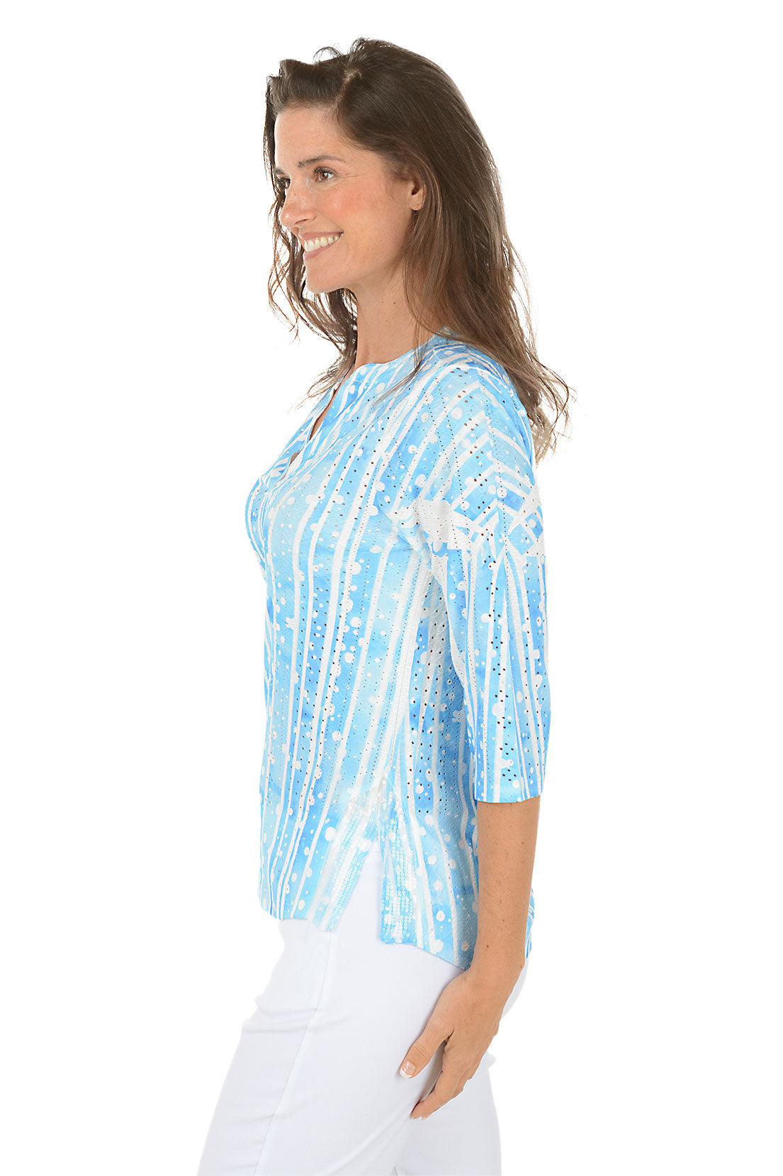 Woman wearing a blue and white patterned blouse on a white background. Side shot.