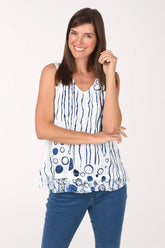 Model wearing the Impulse Underwater View Eyelet Sleeveless Top, white eyelet with navy drip lines and navy bubbles at the hem, over dark jeans, front view