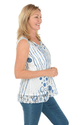 Woman wearing a sleeveless blue and white patterned top on a white background. Side shot.