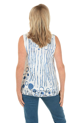 Woman wearing a sleeveless blue and white patterned top on a white background. Back shot.