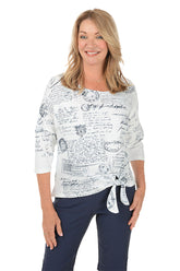 Woman wearing a white blouse with black text and graphics, standing against a white background.