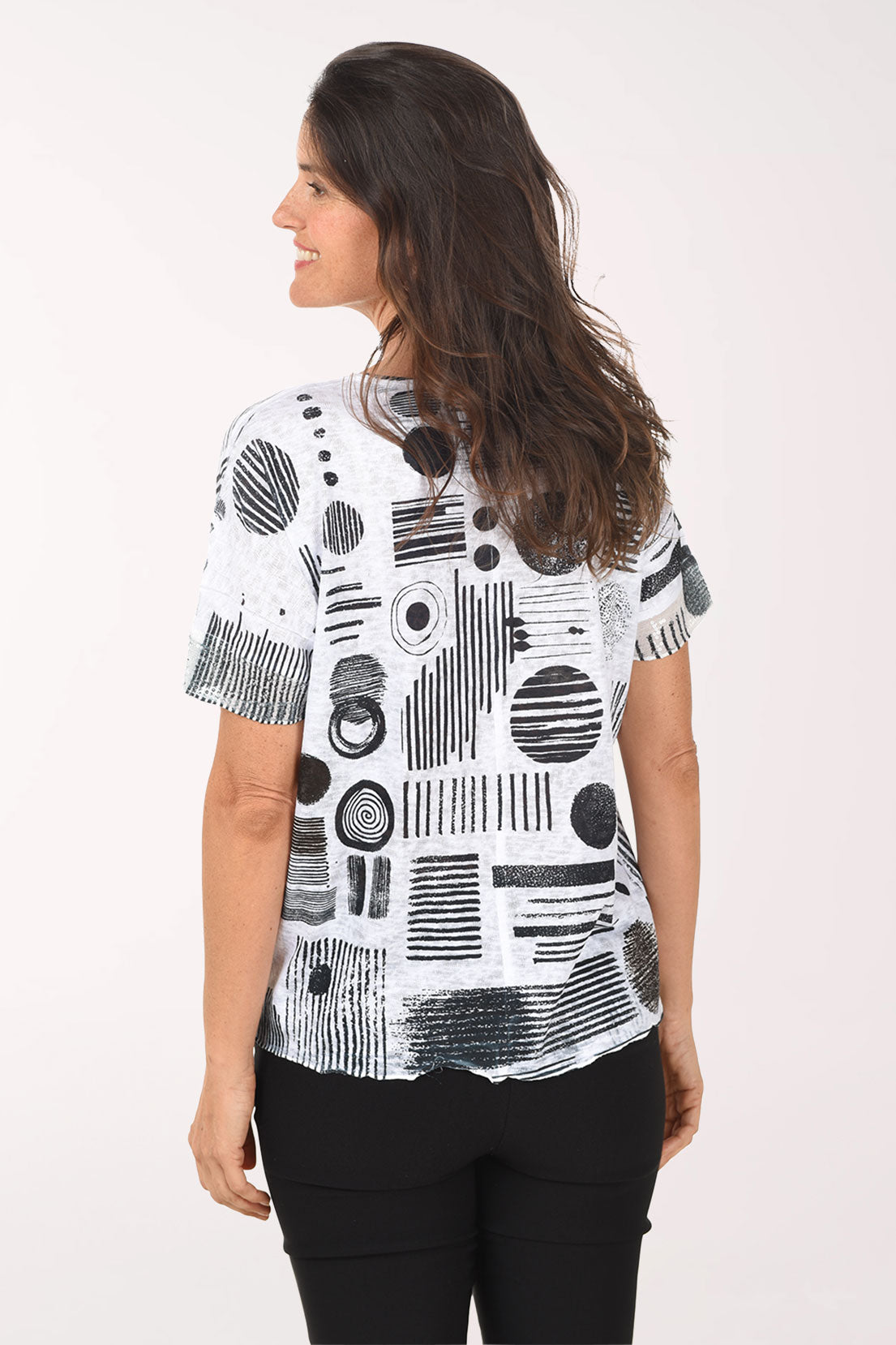Woman wearing a black and white abstract patterned top on a white background