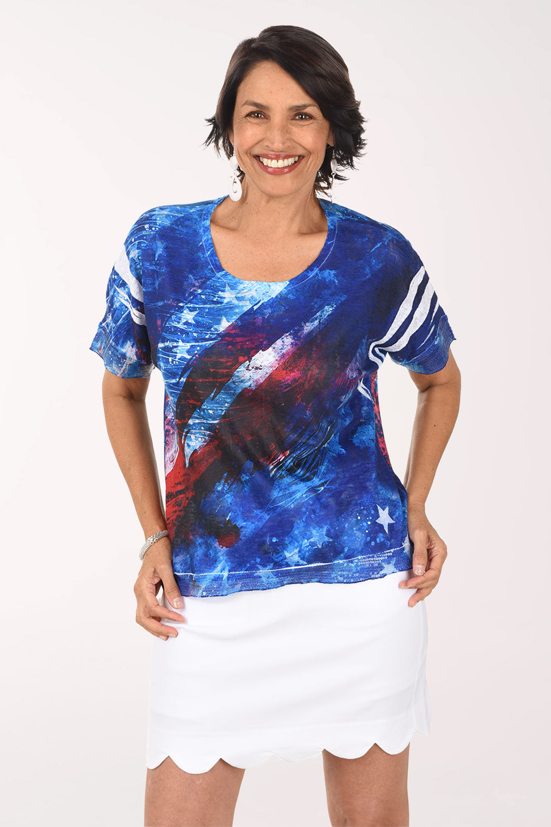 Woman wearing a colorful abstract design shirt with a white skirt on a white background