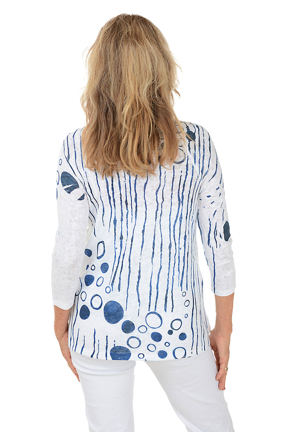 Woman wearing a white top with blue abstract patterns on a white background. Back shot.
