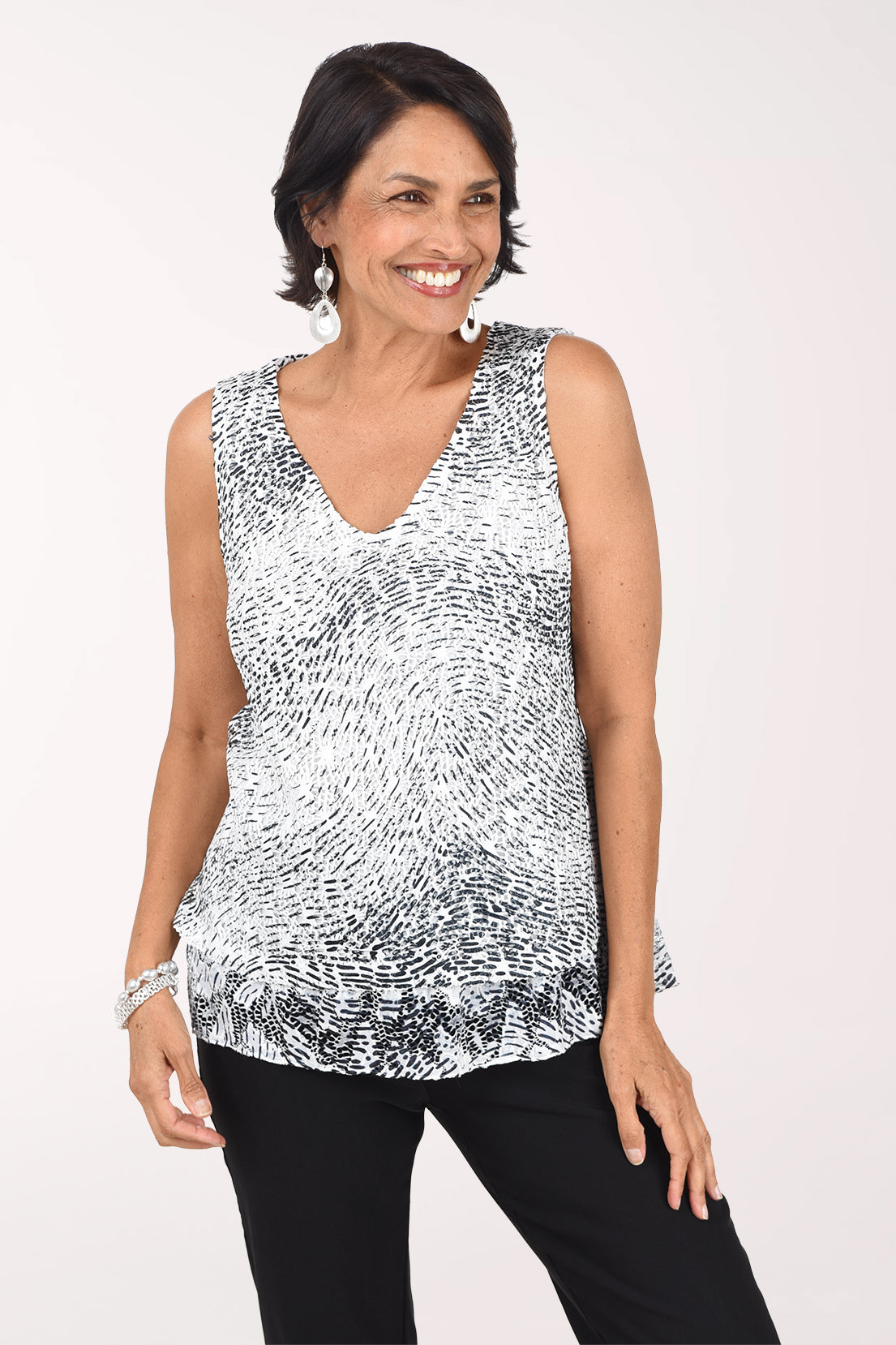 Three-quarter view of the Etched Currents crochet top showing the swirling print and lace hem over black pants.