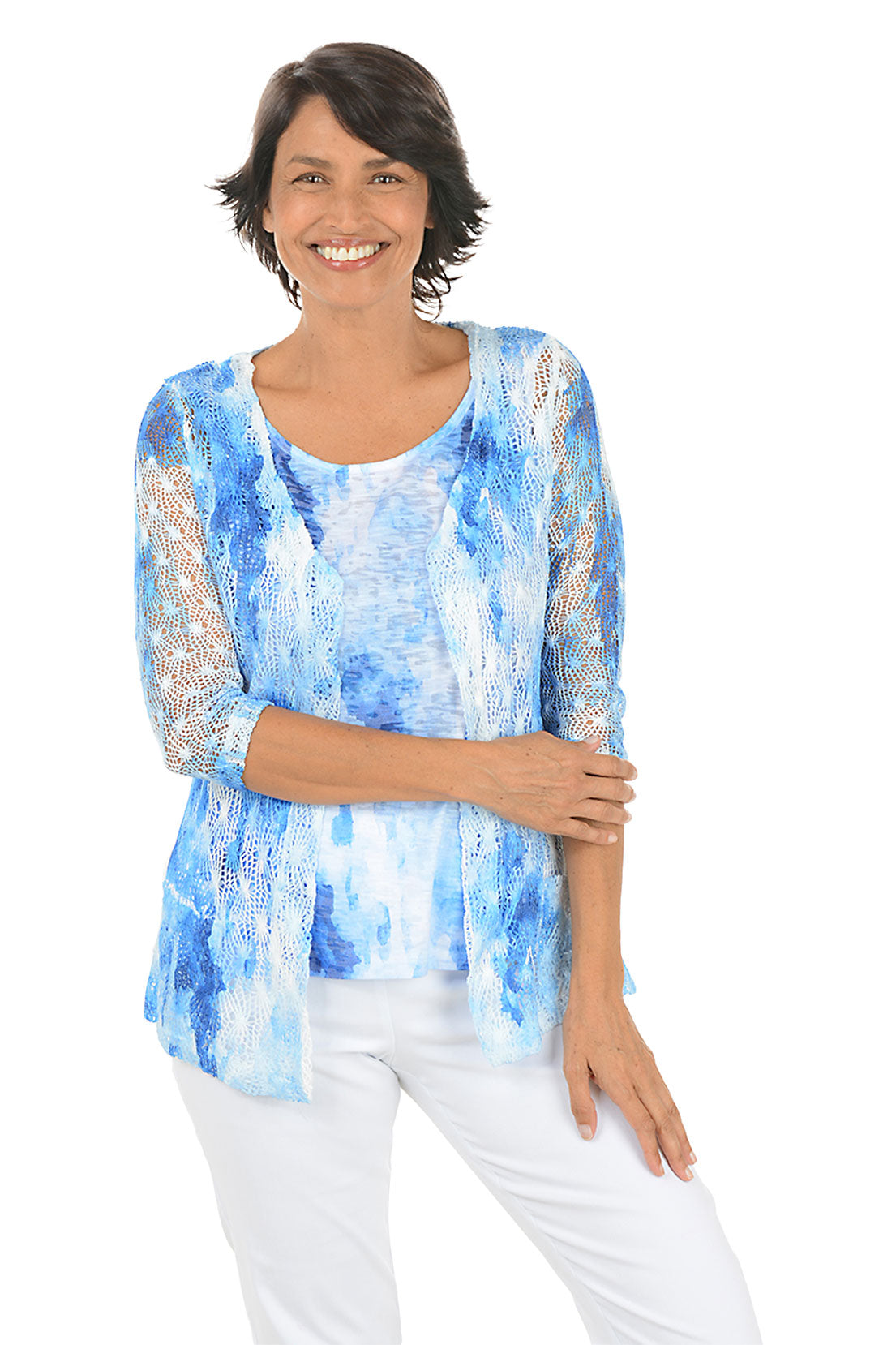 Woman wearing a blue and white patterned top with matching sweater with a plain background.