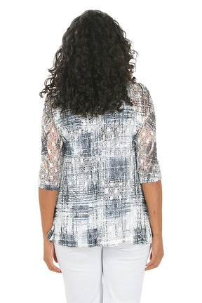 Woman wearing a patterned top with matching sweater and white pants on a white background. Back shot.