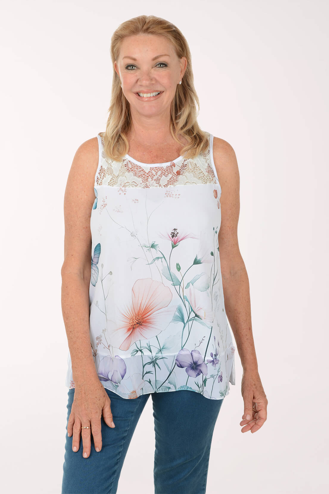 Woman wearing a sleeveless floral top with lace details on a white background