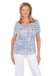 Woman wearing a blue checkered top and white pants on a white background.