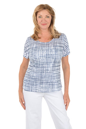 Woman wearing a blue checkered top and white pants on a white background.