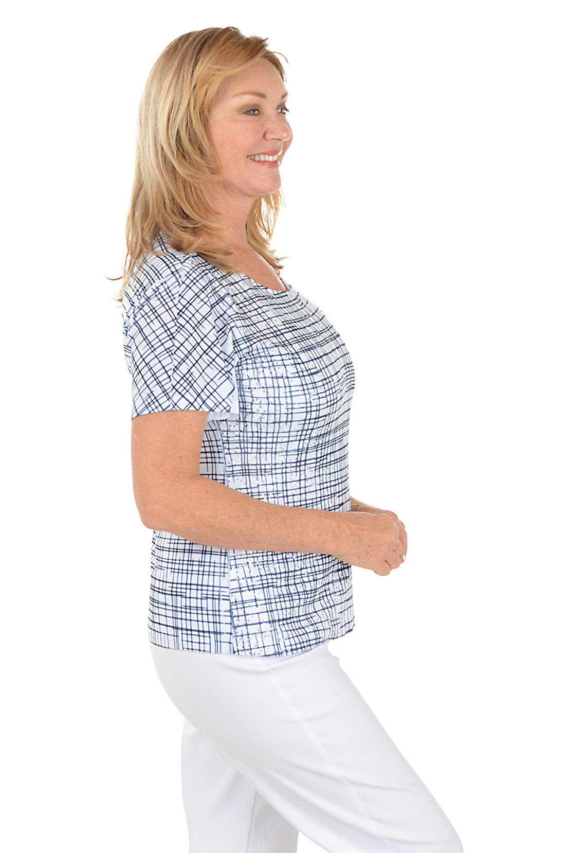 Woman wearing a blue checkered top and white pants on a white background. Side shot.