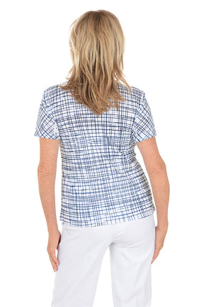Woman wearing a blue checkered top and white pants on a white background. Back shot.