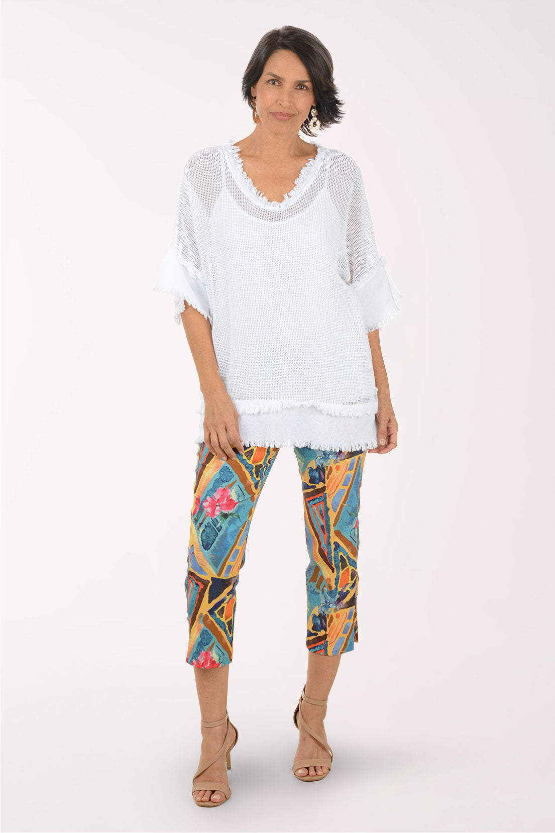 Woman wearing a white top and colorful patterned pants on a white background