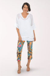Woman wearing a white top and colorful patterned pants on a white background