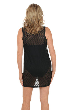 A woman wearing a black sleeveless cover-up with gold metal rings on the sleeves. Back shot.