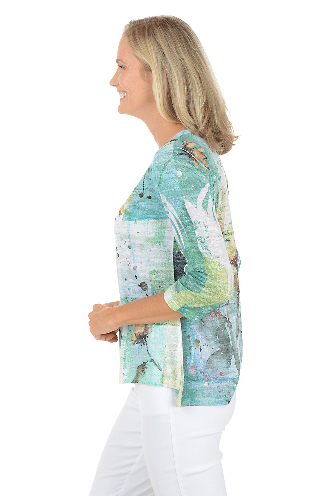 A woman wearing a 3/4 sleeve multicolored top with a sunflower pattern. Side shot.