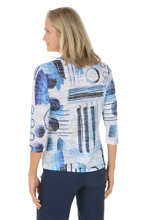 A woman wearing a v-neck 3/4 sleeve blue and white top with an abstract pattern. Back shot.