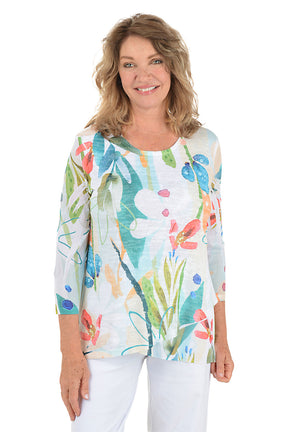 A woman wearing a white 3/4 sleeve abstract floral shirt.