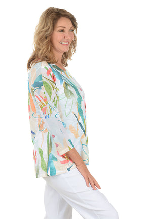 A woman wearing a white 3/4 sleeve abstract floral shirt. Side shot.