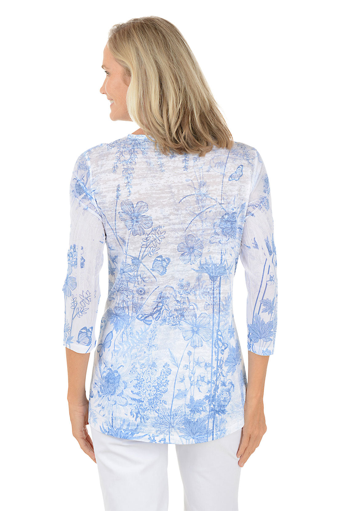 A woman wearing 3/4 sleeve white and blue top with a floral pattern. Back shot.