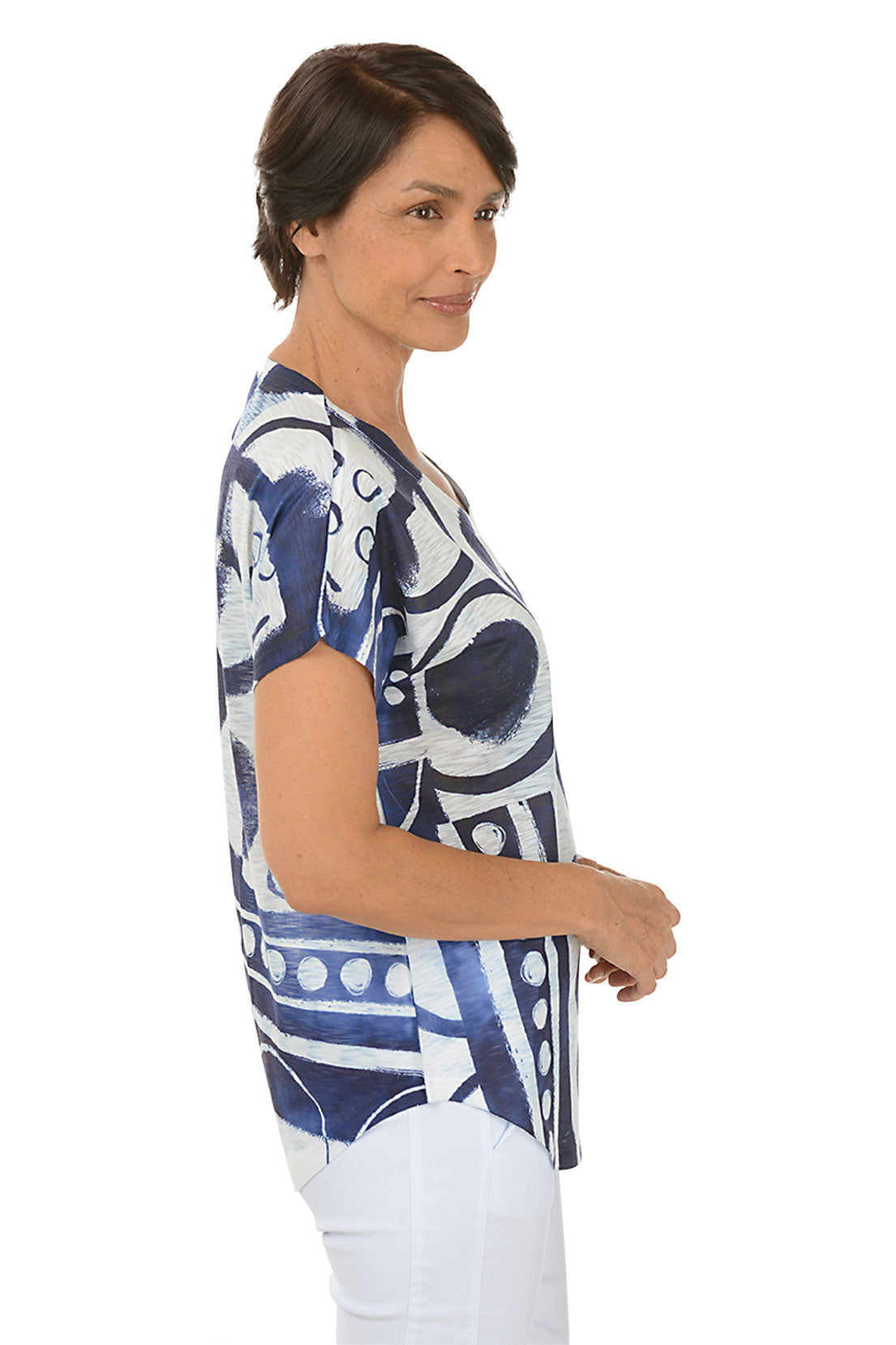 A woman wearing a short sleeve navy and white abstract print shirt. Side short.