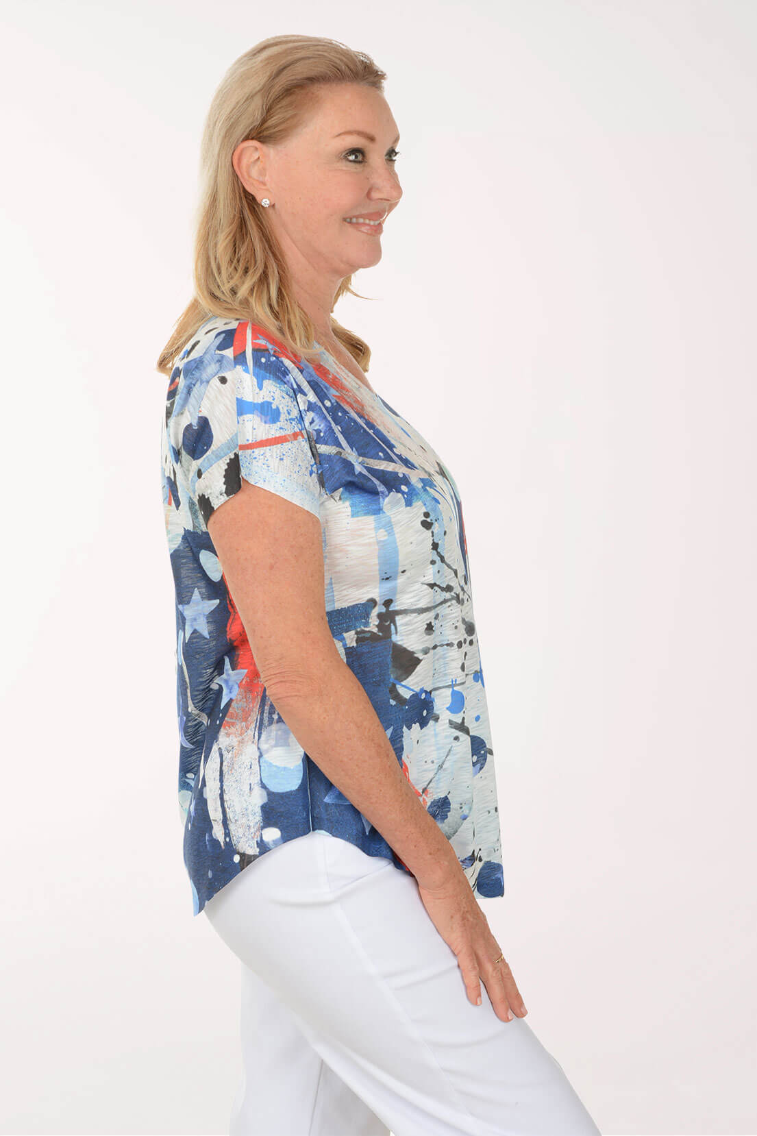 Woman wearing a colorful sleeveless top with abstract patterns on a white background