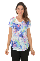 A woman wearing a v-neck short sleeve top with a watercolor floral design.