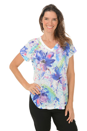 A woman wearing a v-neck short sleeve top with a watercolor floral design. Second shot.