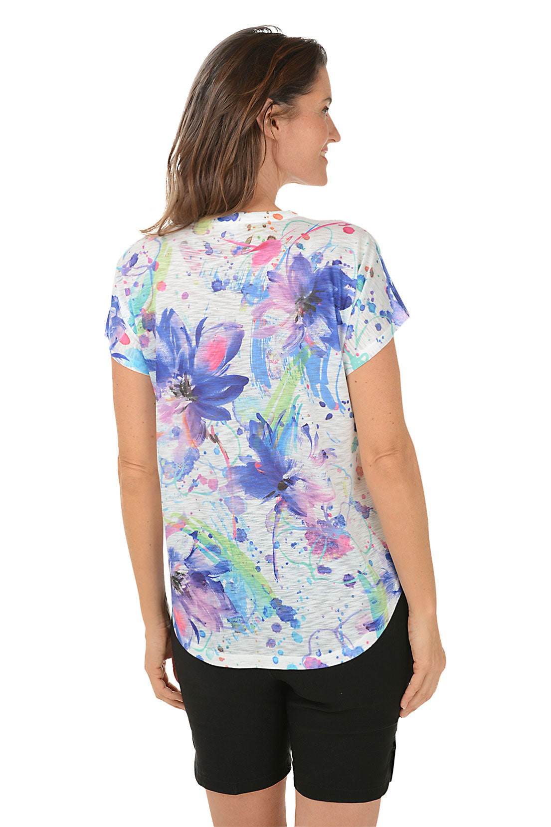 A woman wearing a v-neck short sleeve top with a watercolor floral design. Back shot.