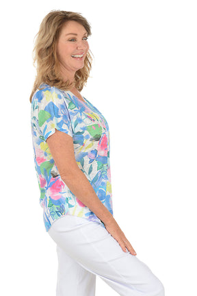 Woman wearing a white short sleeve v-neck shirt with a floral design. Side shot.