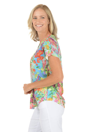 Woman wearing a aqua short sleeve v-neck shirt with a floral design. Side shot.