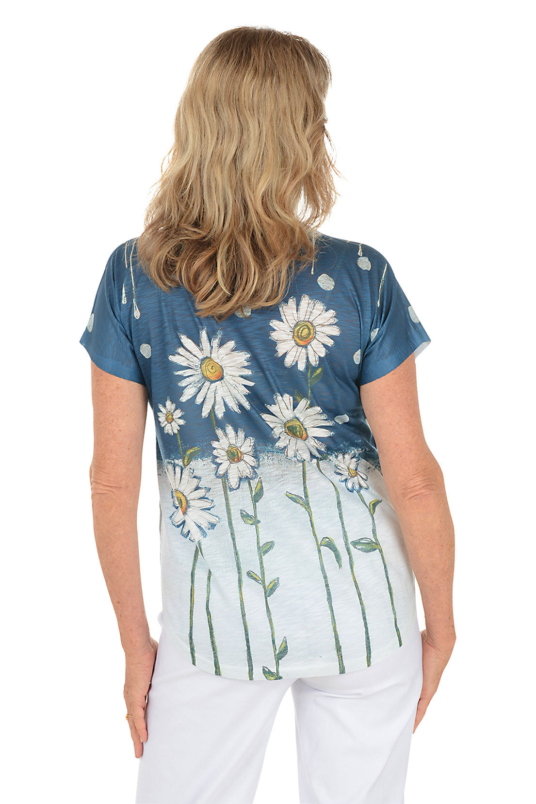 A woman wearing a navy blue and white short sleeve v-neck shirt with a daisy flower design. Back shot.