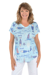 A woman wearing a blue short sleeve v-neck shirt with a fish and sailboat design.