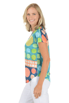 A woman wearing a short sleeve multicolored abstract top. Side shot.