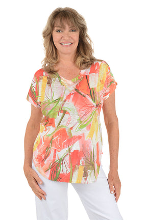 A woman wearing a multi-colored short sleeve v-neck shirt with a floral design.