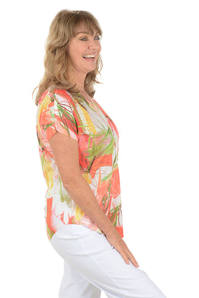 A woman wearing a multi-colored short sleeve v-neck shirt with a floral design. Side shot.