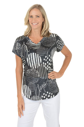 A woman wearing a black and white short sleeve v-neck shirt with an abstract design.