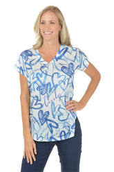 A woman wearing a blue and white short sleeve v-neck shirt with a heart design.