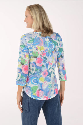 Woman wearing a colorful floral long-sleeve top against a white background