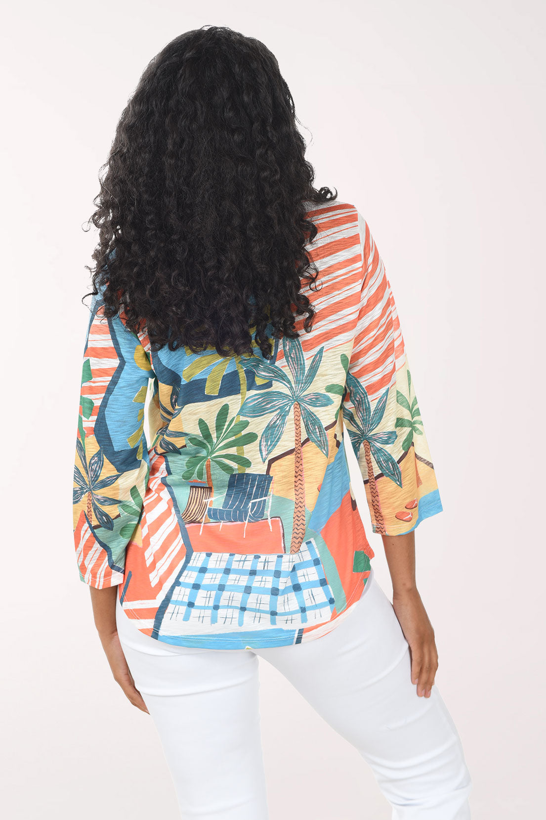 Woman wearing a colorful patterned shirt with palm tree design on a white background
