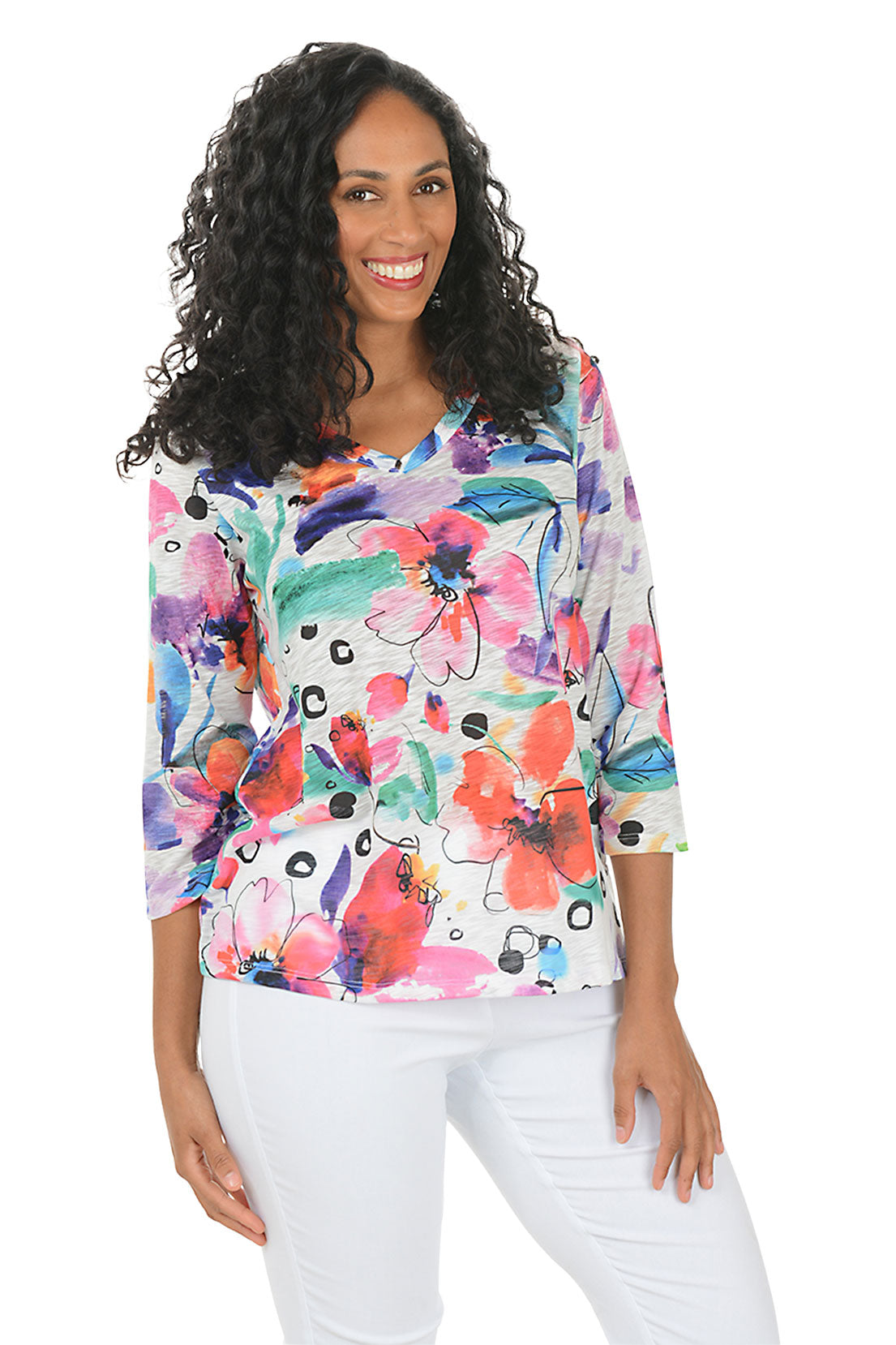 Woman wearing a colorful floral blouse with white pants on a white background.