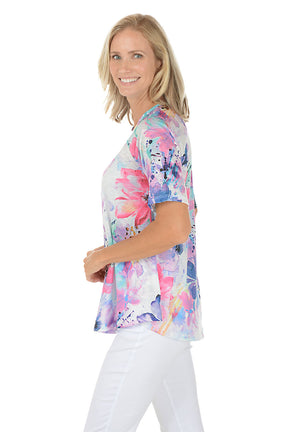 A woman wearing a purple short sleeve shirt with a floral pattern. Side shot.