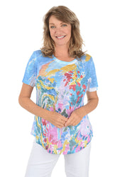 A woman wearing a blue short sleeve top with an abstract floral pattern.