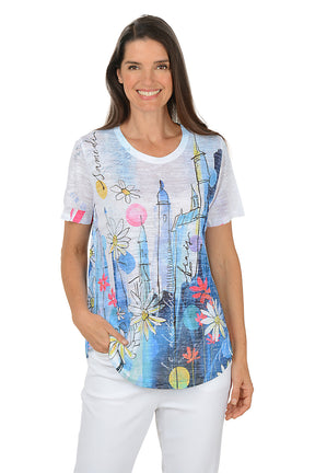 Woman wearing a colorful graphic t-shirt with a white background. Second front shot.